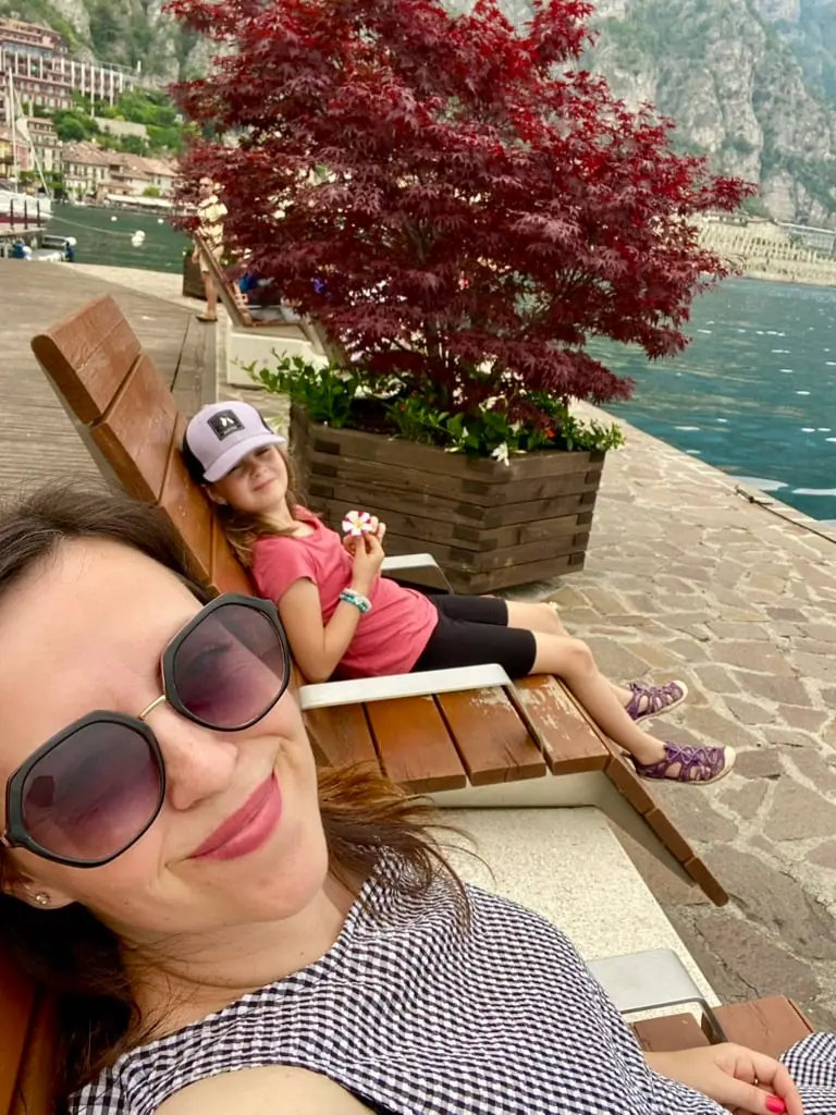 Monča a Niky relaxují na dřevěném lehátku v přístavu na molu v Limone sul Garda, s výhledem na jezero Garda.