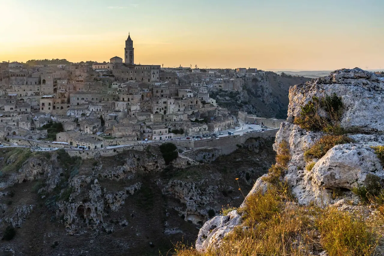 Ikonický panoramatický pohled na celé město Matera se Sassi di Matera z vyhlídky Belvedere di Murgia Timone na protějším svahu kaňonu