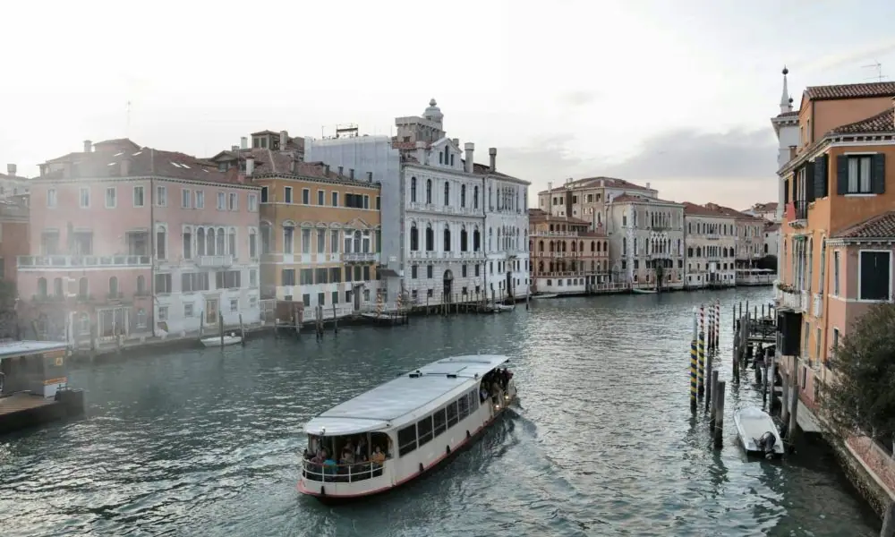 Peaceful canal in Venice with a boat passing by historic buildings.