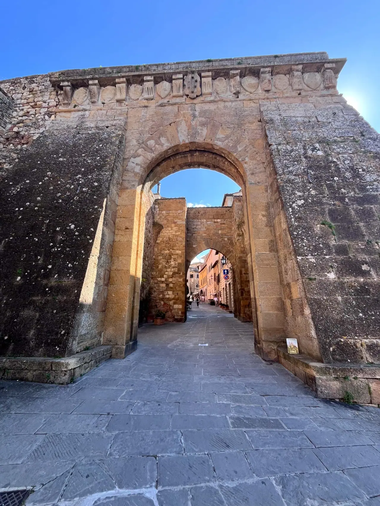 Historická kamenná brána s ozdobným frízem vedoucí do středověkého centra Montepulciana, kde jsme s Monči a dětmi objevovali toskánské vinařské město