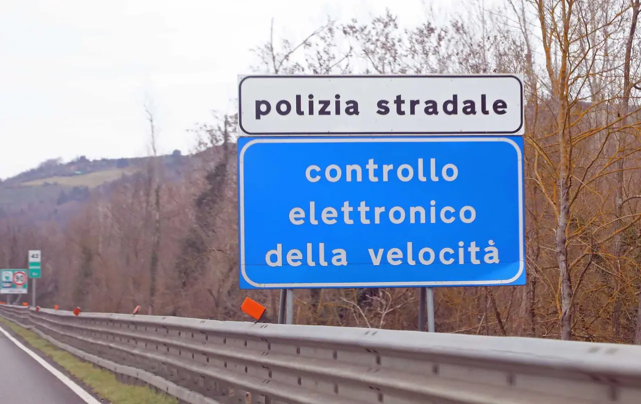 Modrá dopravní cedule na italské dálnici upozorňující na elektronické měření rychlosti policií, kterou jsme potkali během naší cesty