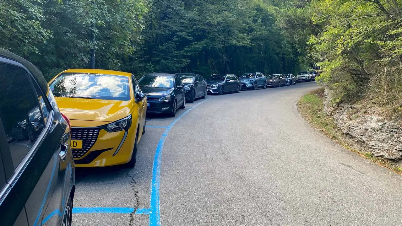 Dlouhá kolona aut parkujících na silnici vedoucí k lázním Bagni San Filippo v Toskánsku