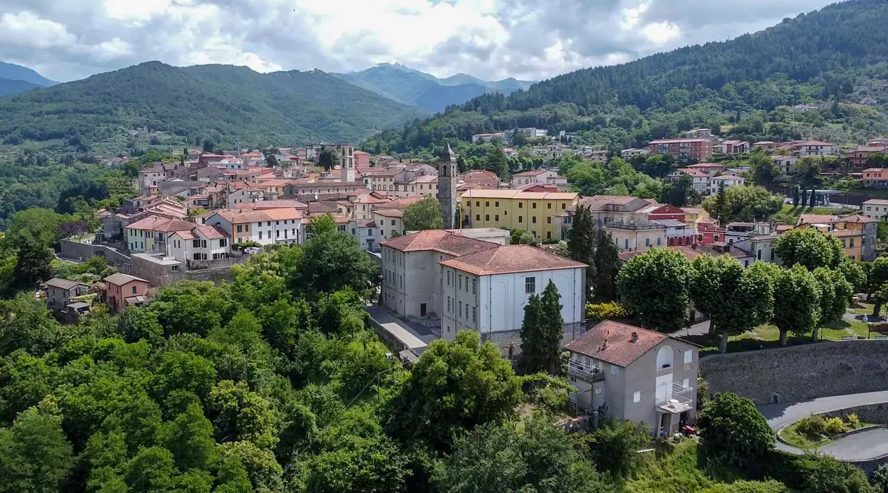Letecký pohled na městečko Fivizzano s červenými střechami domů, kostelní věží a zelenými kopci Toskánska v pozadí