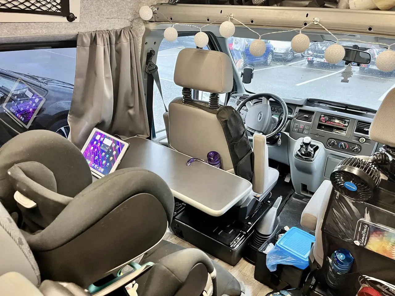 Dokončený interiér naší přestavěné dodávky Transit s otočnými sedadly, stolkem, tabletem a dekoračním osvětlením připraveným na italské dobrodružství