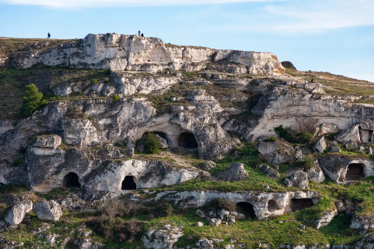Jeskyně vytesané do skály na protějším svahu nad údolím Gravina v přírodním parku Murgia Materana