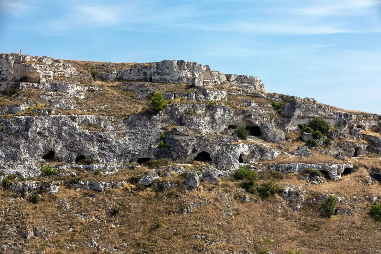 Neolitické jeskyně vytesané do vápencové skály na protějším svahu kaňonu Gravina kde lidé žili před 7000 lety naproti městu Matera