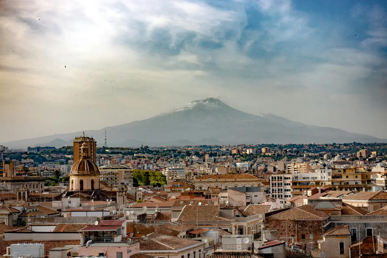 A breathtaking cityscape of Catania, Sicily with Mount Etna in the background, showcasing urban and natural beauty.