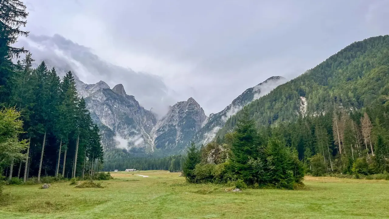 Horské štíty v mracích nad loukou u jezer Fusine