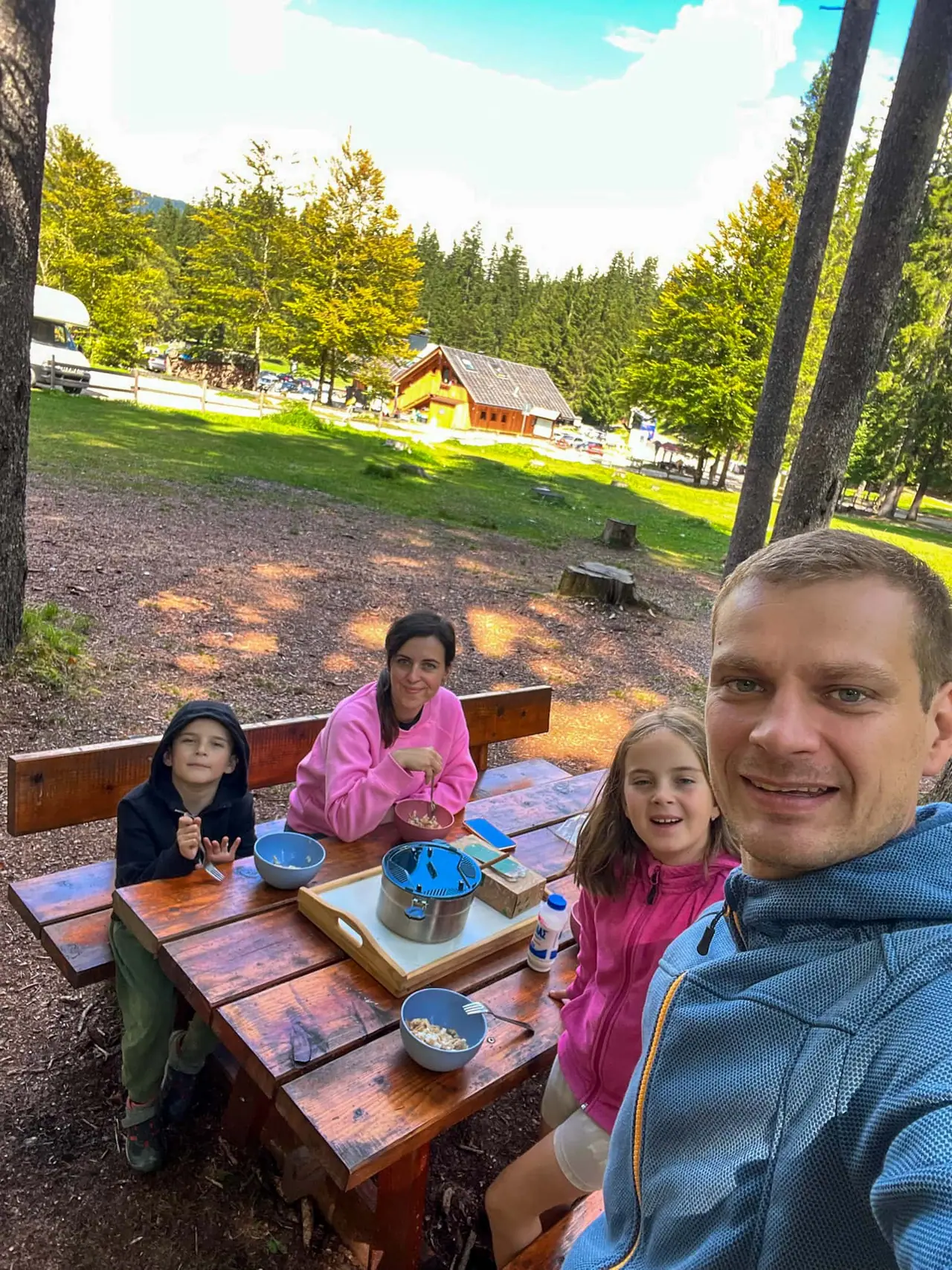Rodinný oběd u venkovního posezení u Lago di Fusine – vlastní vaření na cestách