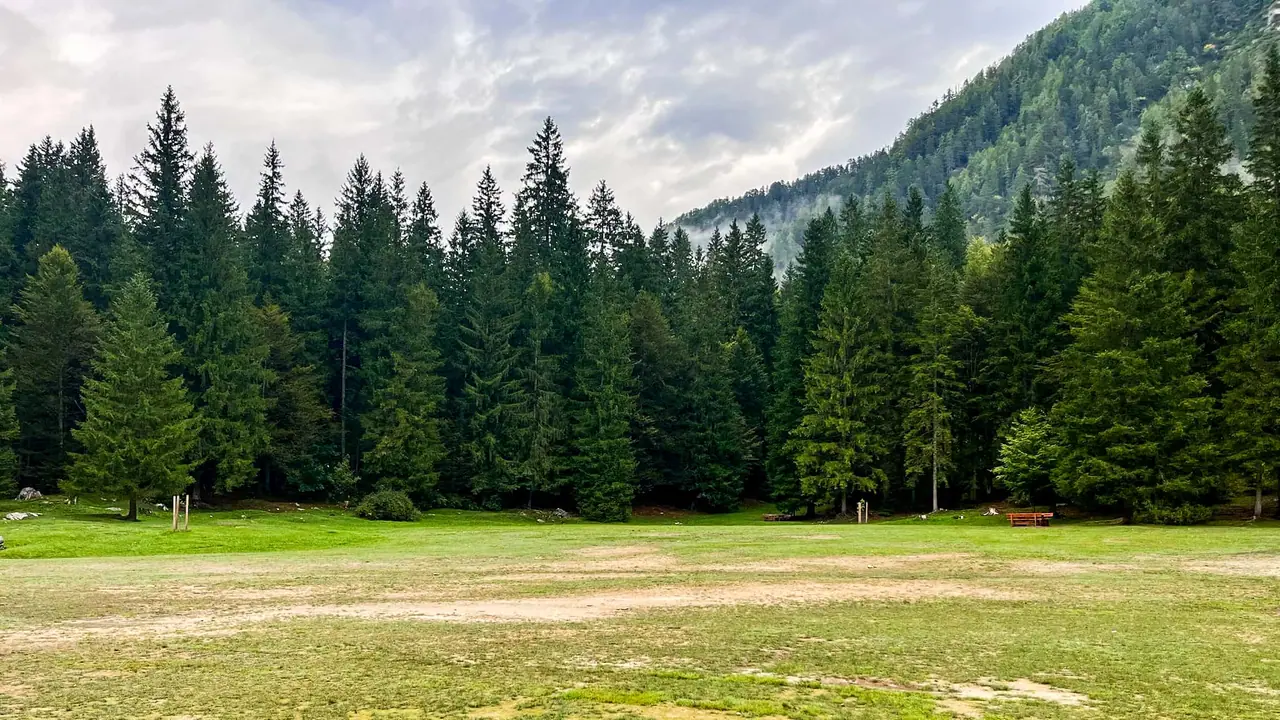 Zatravněný plácek s lavičkami u Lago di Fusine směrem k hornímu jezeru