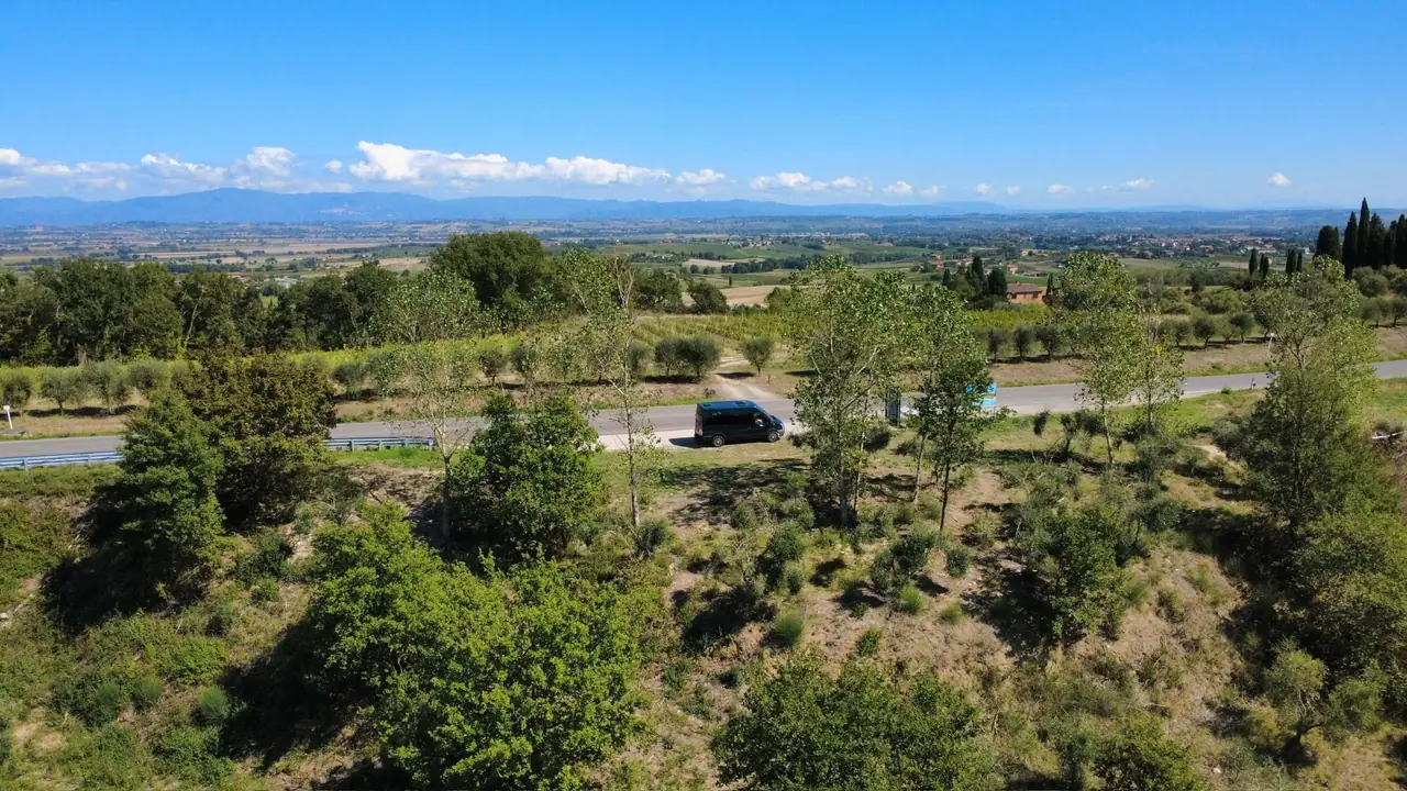 pohled z mého dronu na toskánskou krajinu u Lucignana s naším autem na silnici mezi zelenými poli a stromy