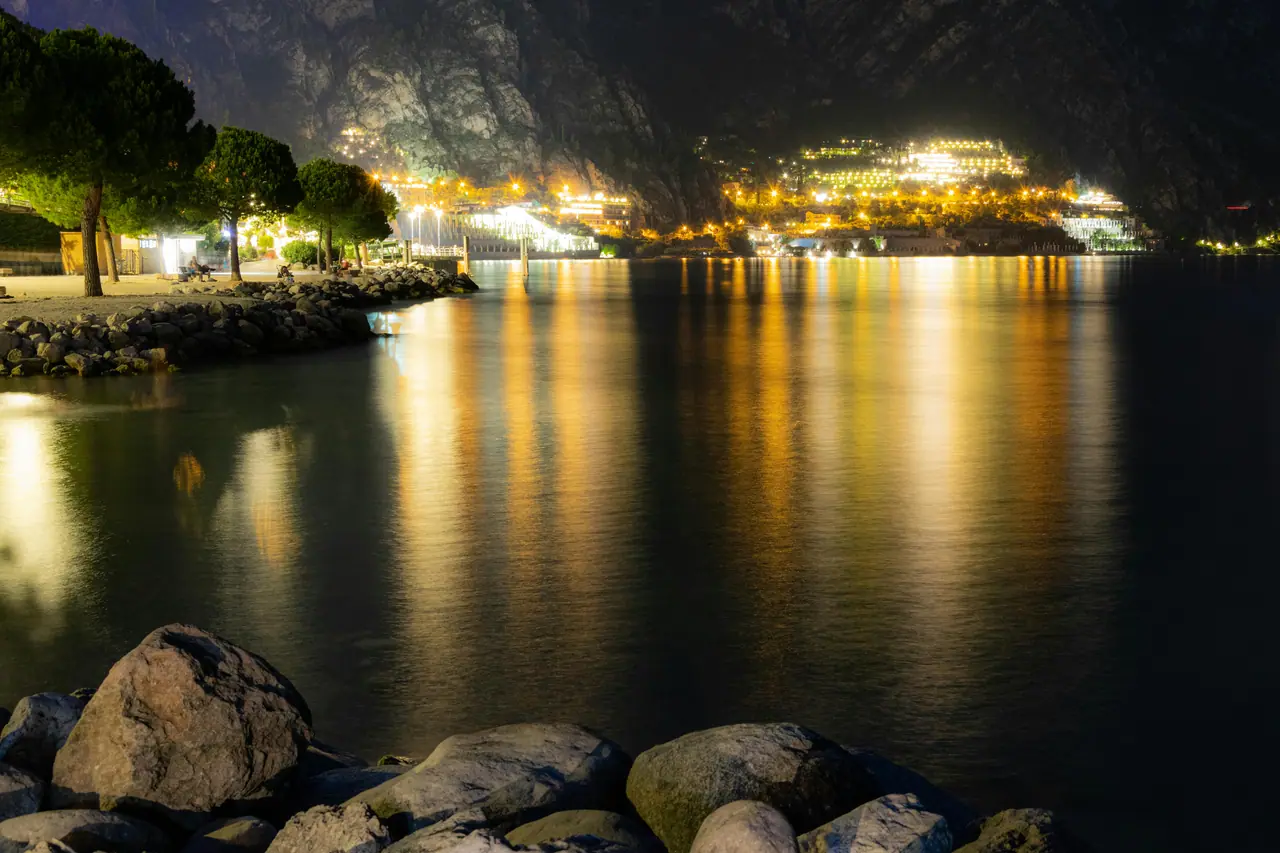 Úchvatný noční výhled na Limone Sul Garda s odrazy městských světel na jezeře, vytvářející fascinující atmosféru.