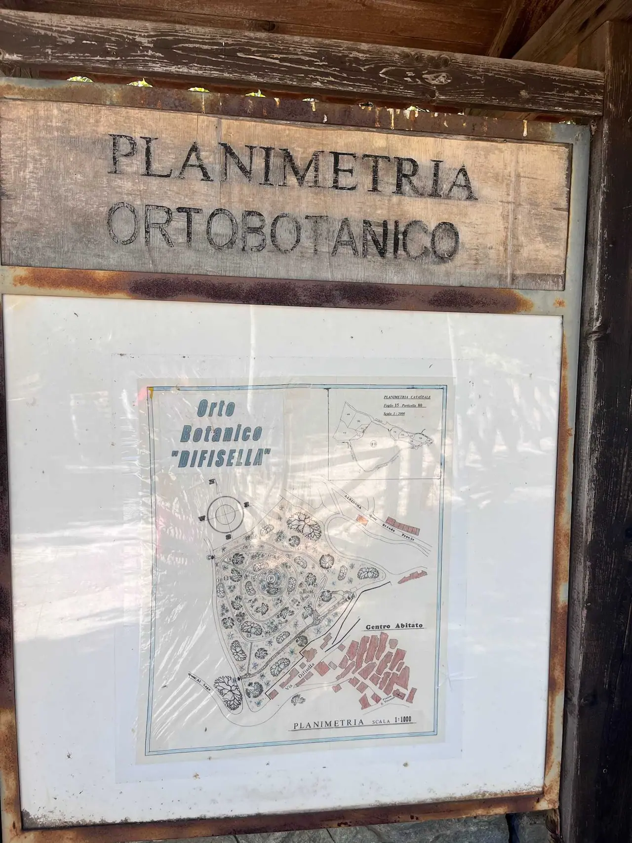 Starý dřevěný informační panel s mapou botanické zahrady Difisella v Alessandria del Carretto, zobrazující rozmístění rostlin a turistické centrum