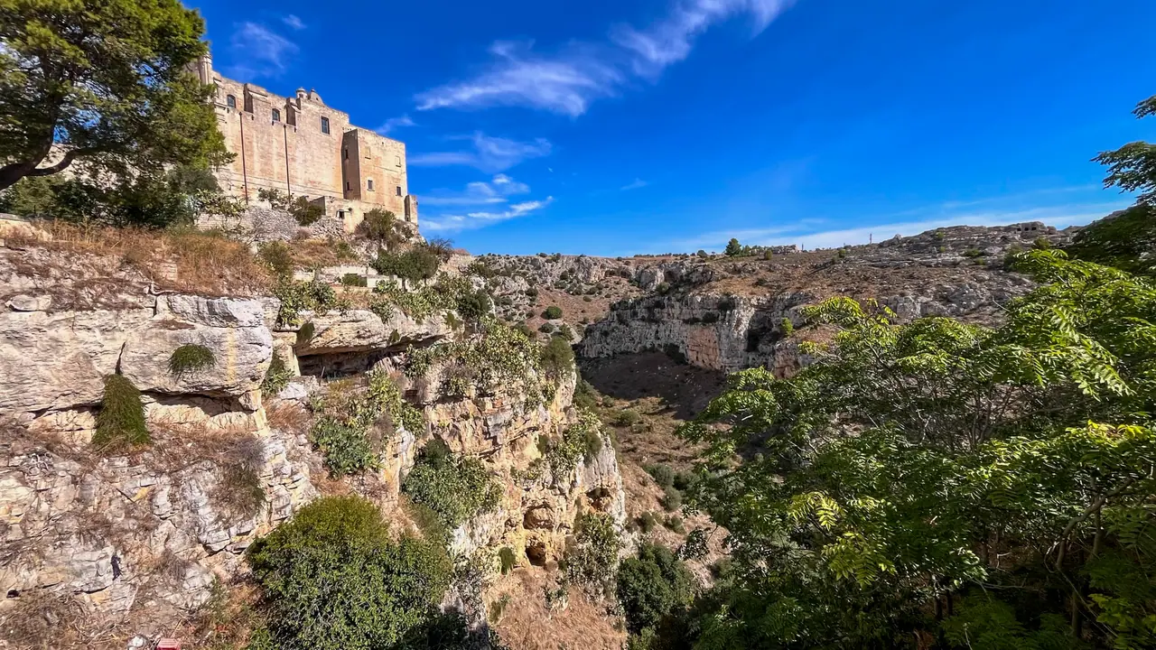 Kaňon Gravina se skalními stěnami a jeskyněmi pod kamennými domy Matery