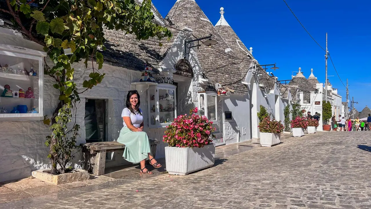 Monča sedí u trulli obchodu s řemeslnými výrobky v historické čtvrti Rione Monti v Alberobellu, Apulie