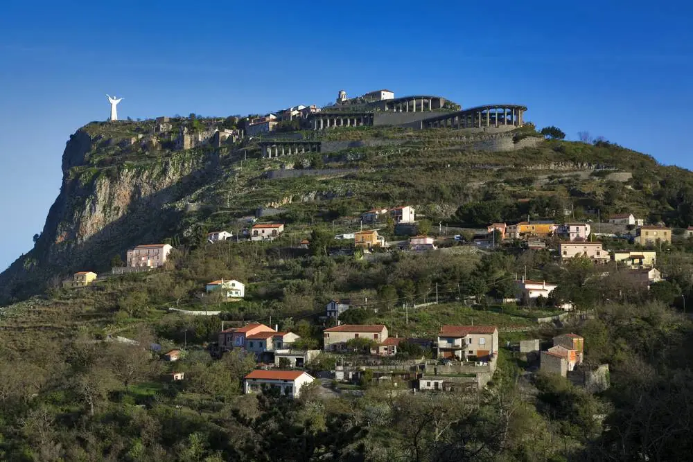 Vesnice Maratea s bílou sochou Krista na vrcholu Monte San Biagio, domy rozeseté po zalesněném svahu nad údolím