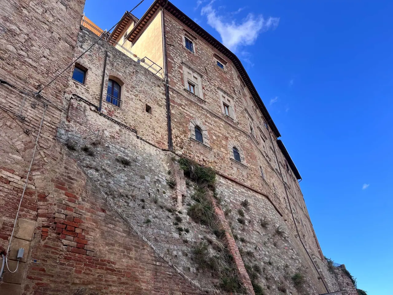 Vysoké kamenné hradby Montepulciana s cihlovou věží, kde jsme s Monču a dětmi obdivovali staré toskánské opevnění pod modrým nebem