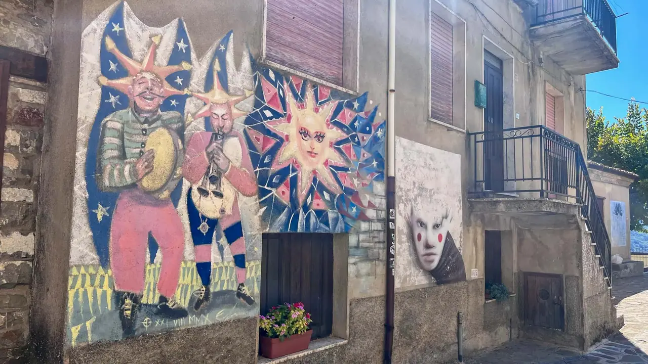 Mural s folklorními maskami v Alessandria del Carretto