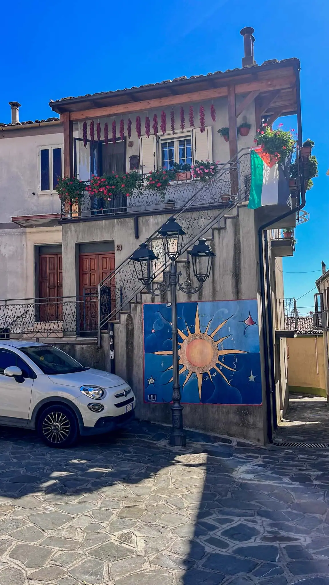 Murál se sluncem a měsícem na fasádě domu v Alessandria del Carretto
