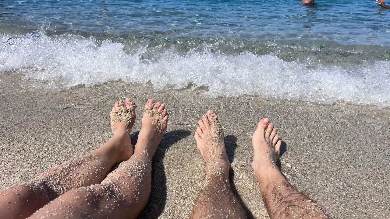 Naše nohy odpočívají v jemném písku na pláži v Tropei, zatímco vlny moře si hrají u našich chodidel