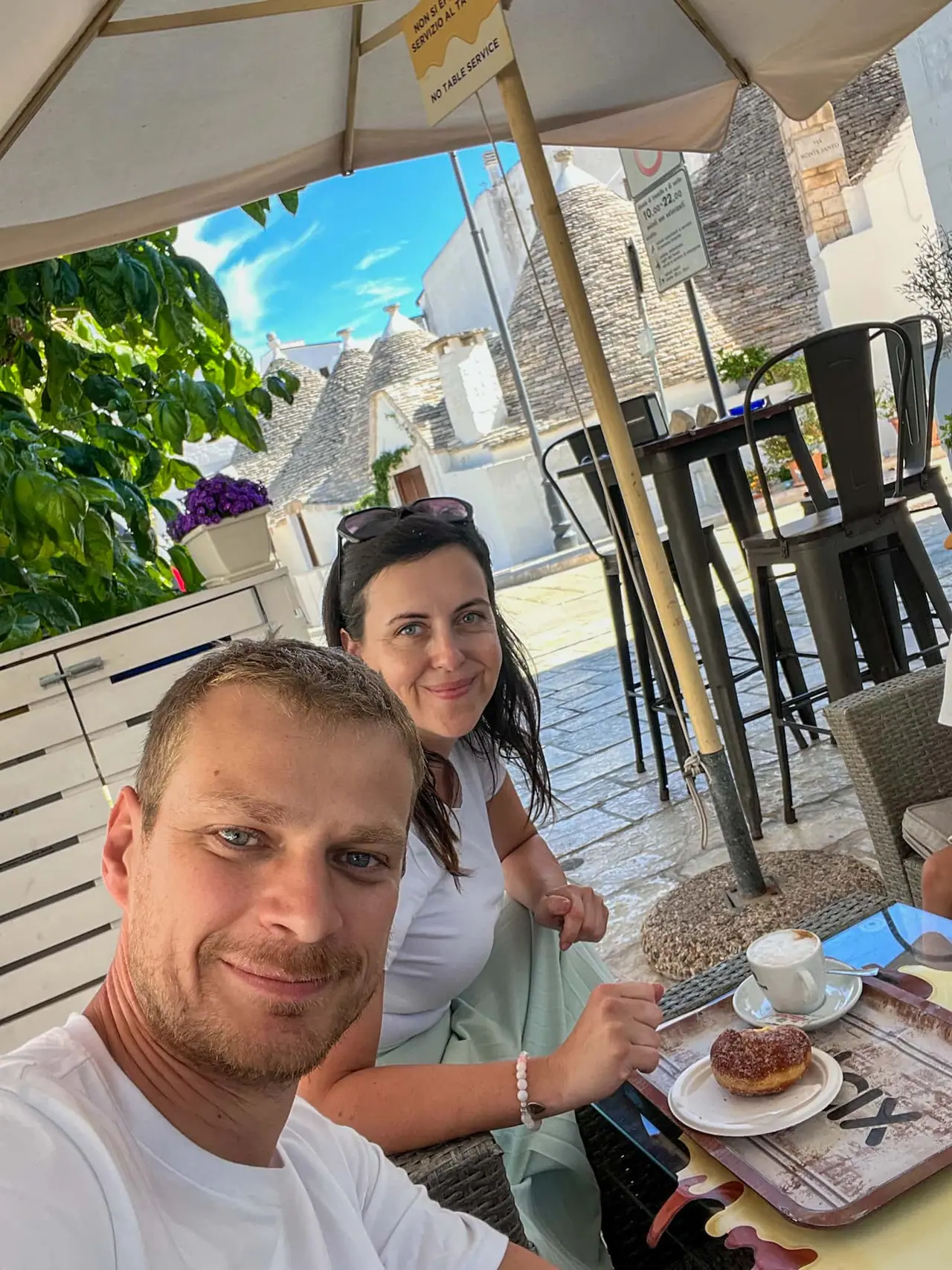 Užíváme si kávu a bombolone na terase kavárny s výhledem na trulli domečky v Alberobellu