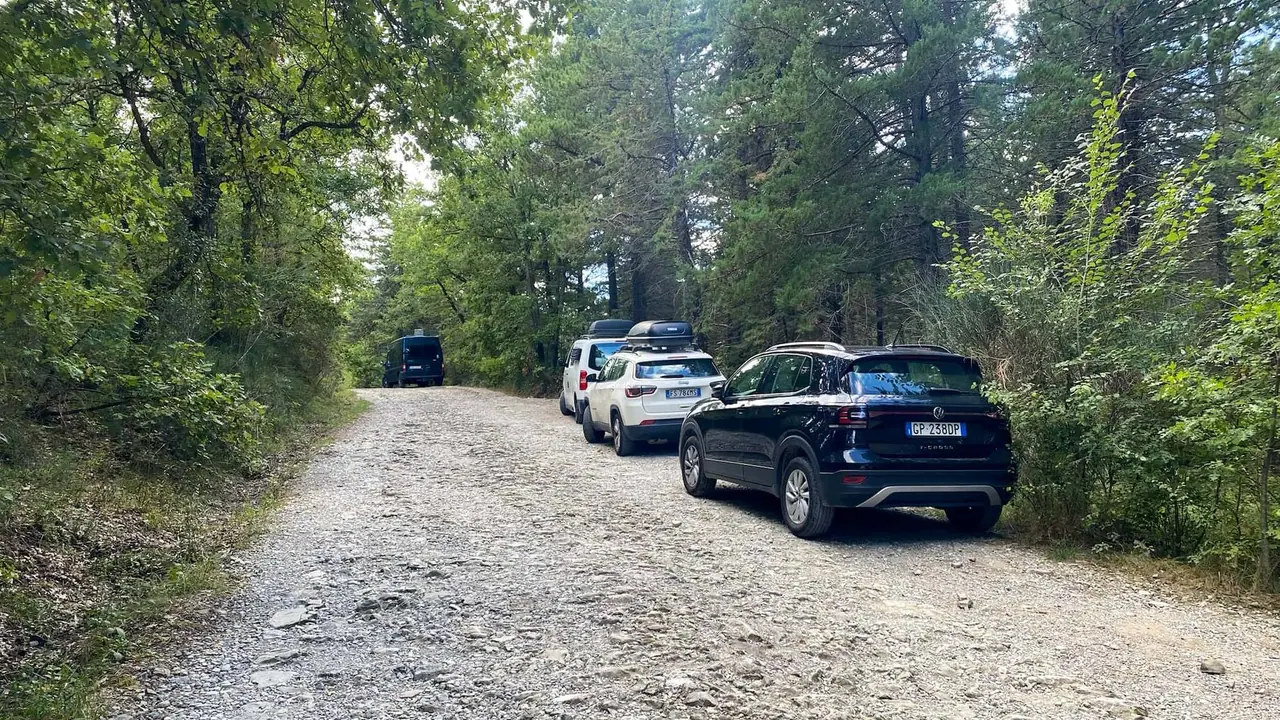 Naše auto zaparkované na štěrkové cestě mezi stromy před návštěvou termálních pramenů v Bagni San Filippo v Toskánsku. Místo které nám doporučili místní.
