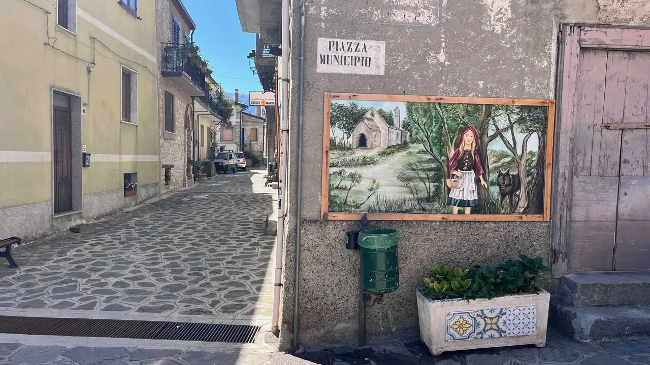 Hlavní náměstí v Alessandria del Carretto s nástěnnou malbou místní tradice, kamennou dlažbou a typickou jižně italskou architekturou