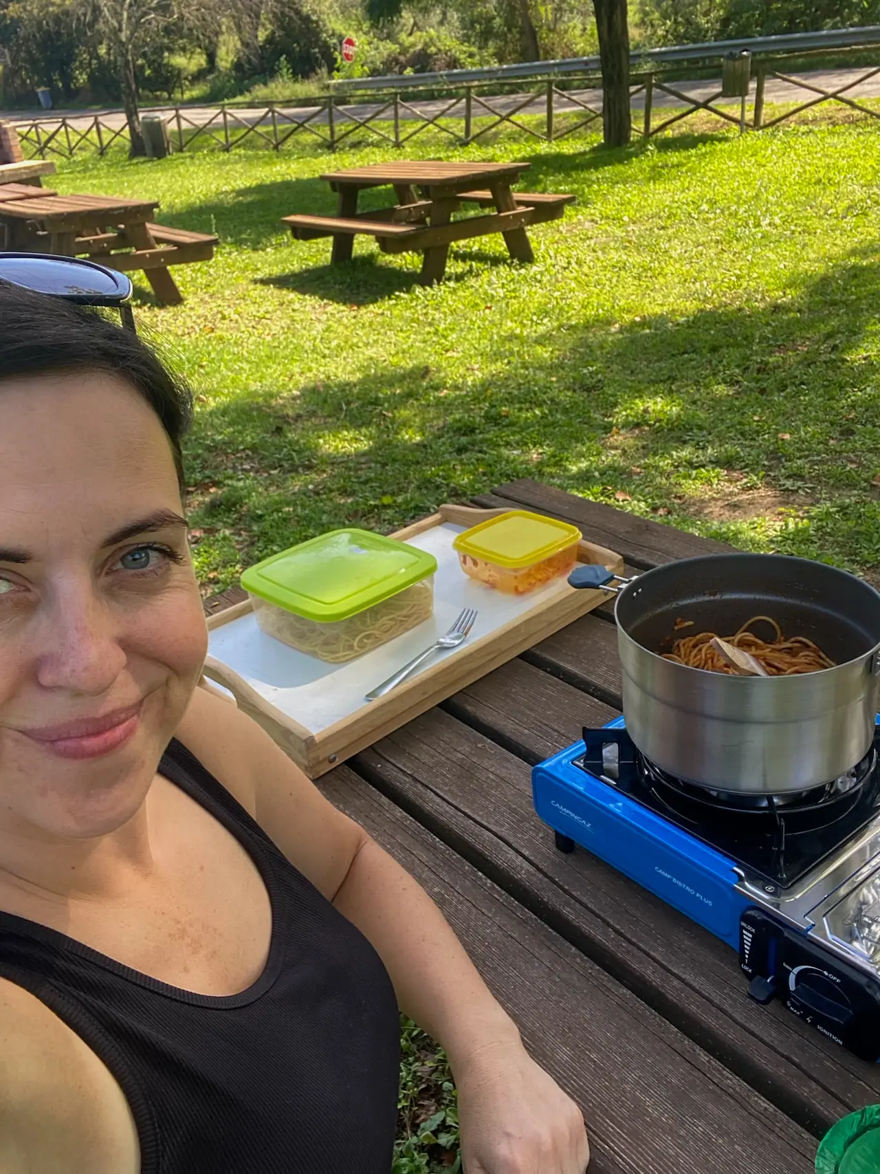 Piknikové místo u Vetriola, kde žena připravuje oběd na cestovním vařiči u dřevěného stolu v přírodě.