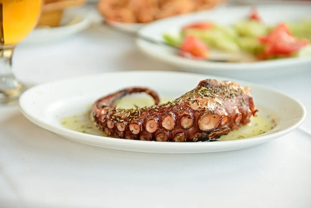 Grilovaná chobotnice (Polpo alla griglia) servírovaná s citronem a petrželkou v restauraci u moře ve Vieste, Itálie