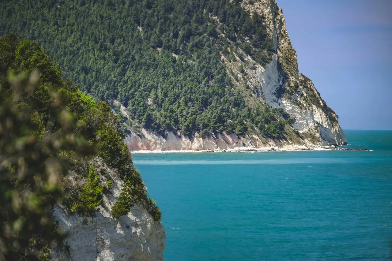 Beautiful turquoise waters and lush cliffs of Monte Conero, Italy captured in daylight.
