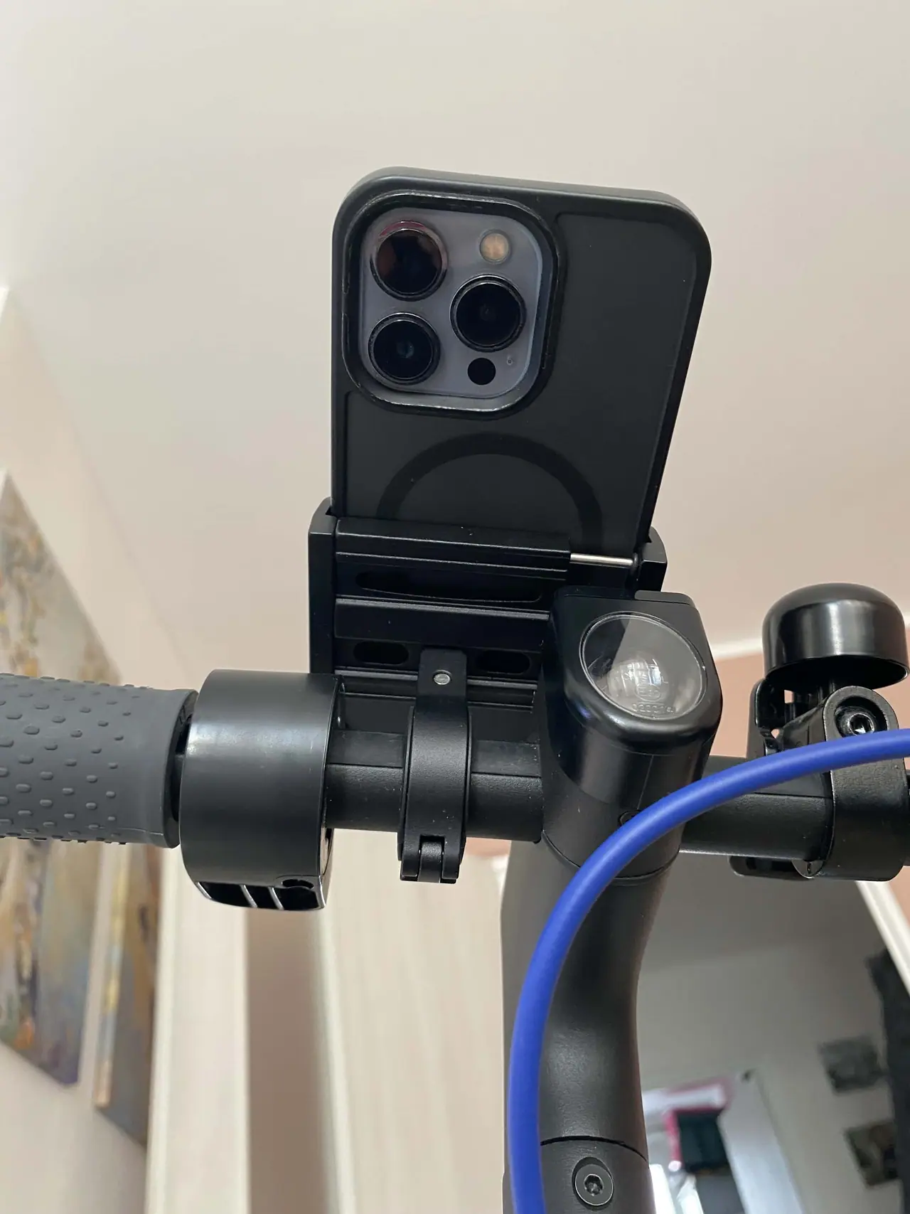 Černý iPhone připevněný v kovovém držáku Swissten BC2 na řídítkách kola s modrým kabelem