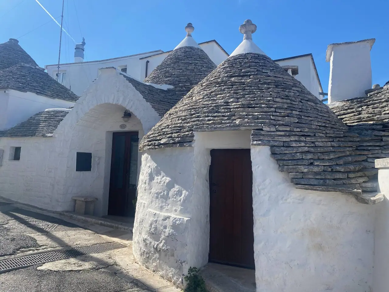 Bílé trulli s kuželovitými kamennými střechami a ozdobnými komínky v historickém centru Alberobella v Puglii