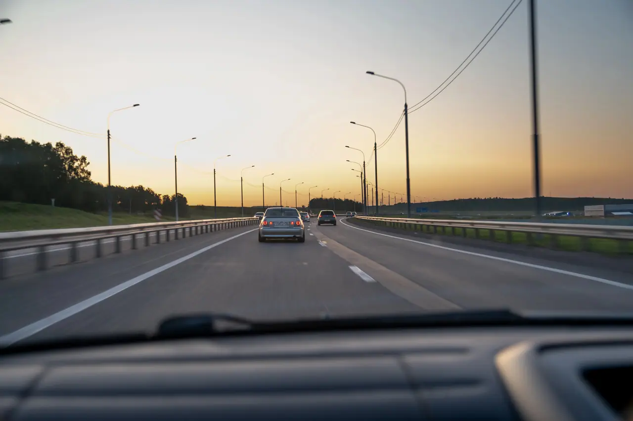 Pohled z auta při jízdě po dálnici za soumraku – cestování vlastním vozem.