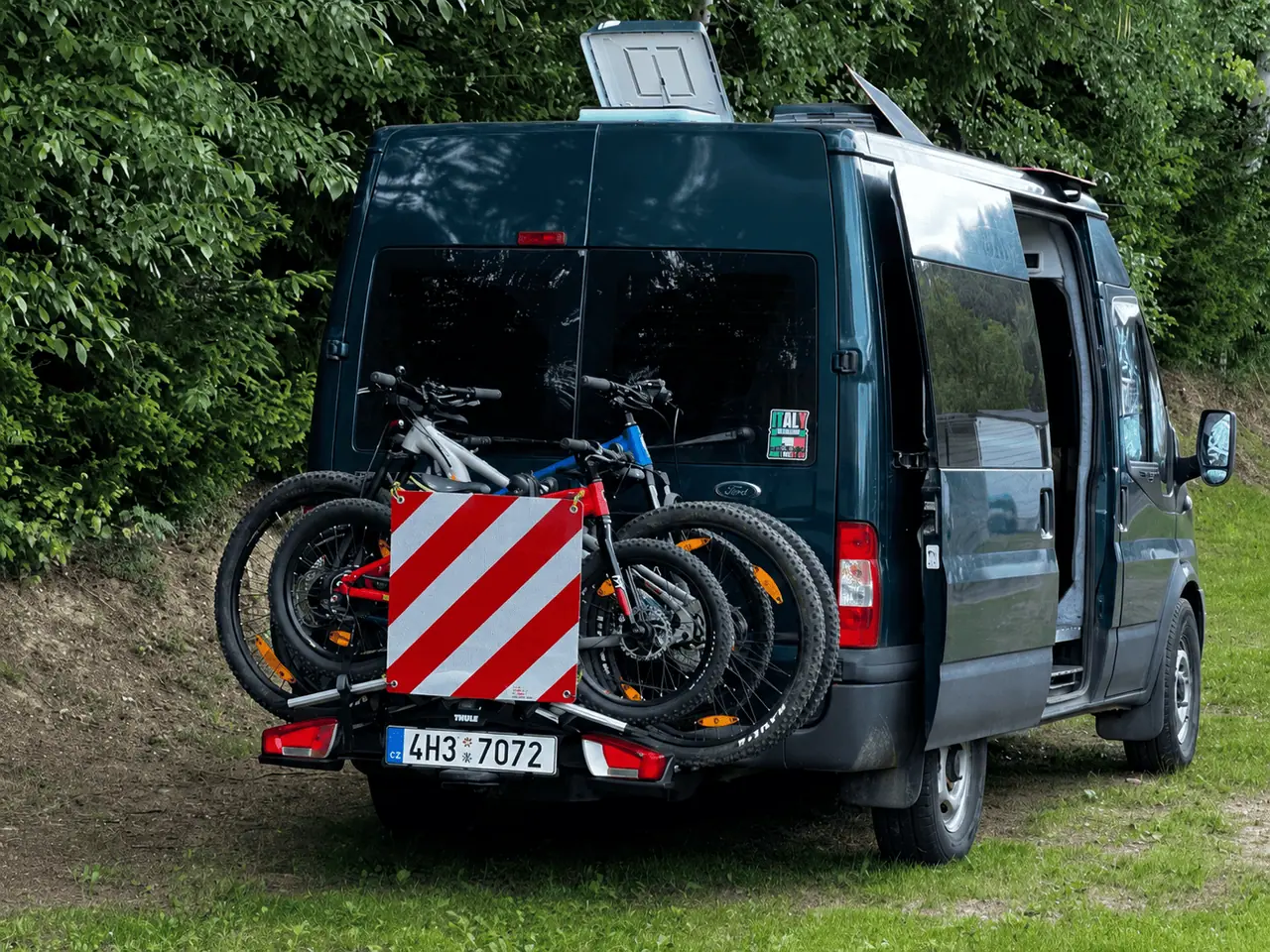 Dodávka Ford Transit s koly na nosiči a výstražnou značkou BICMA 50×50 cm, SPZ zůstává čitelná